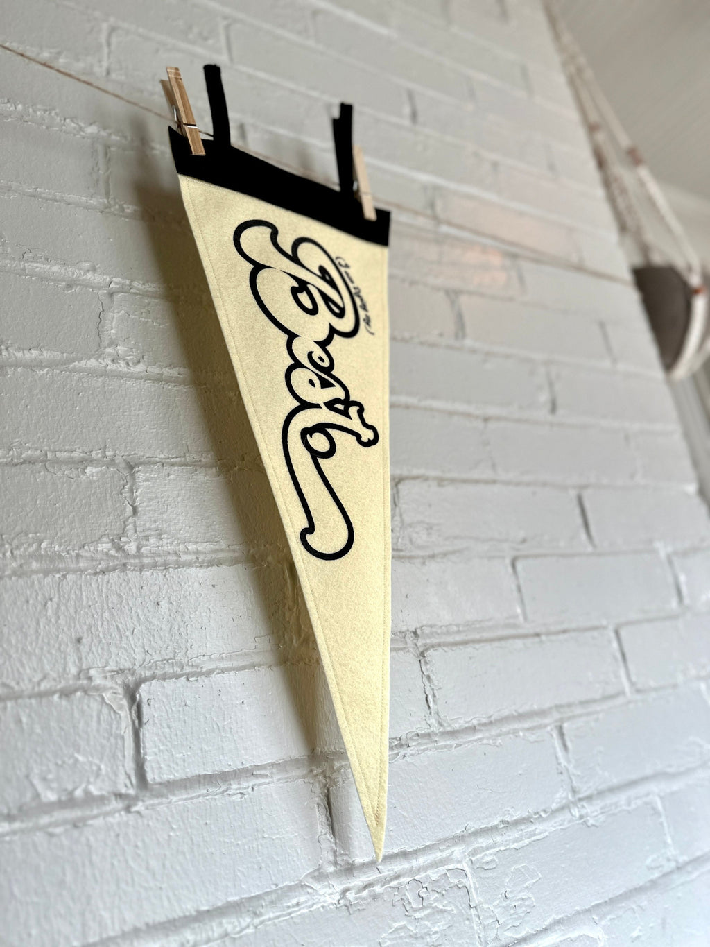 Side view of a cream felt pennant with black trim and black lettering that reads "I'm trying my best"