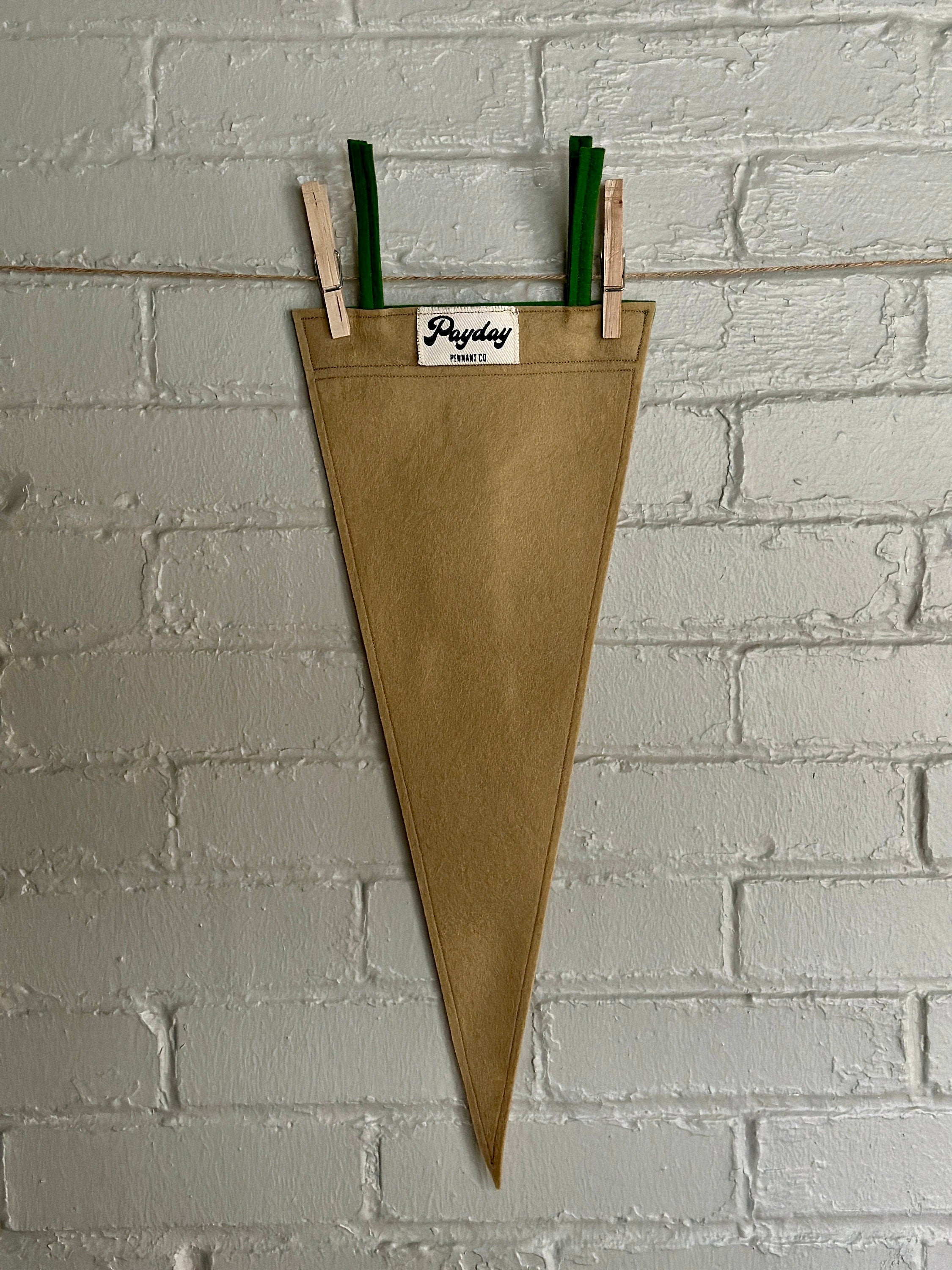 Back of a light brown felt pennant with green trim and green flowy lettering that reads "Let's go outside"