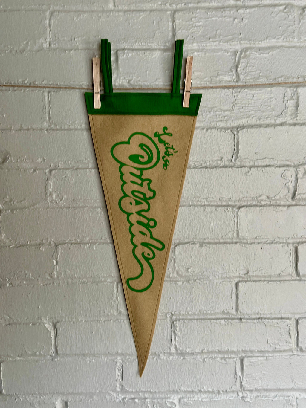 Light brown felt pennant with green trim and green flowy lettering that reads "Let's go outside"