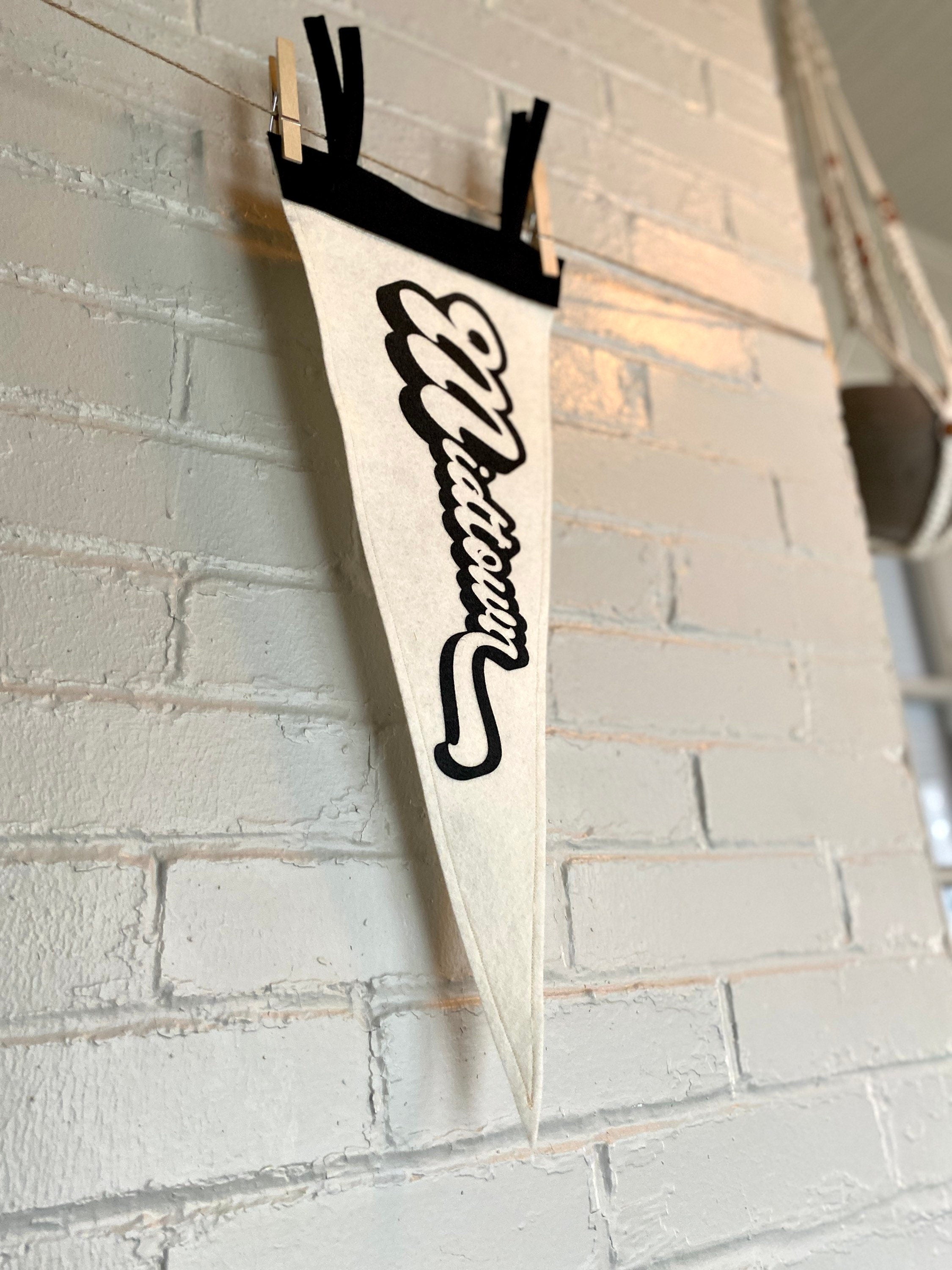A canted side photo of a black and white pennant that reads "Midtown" with the pennant vertical