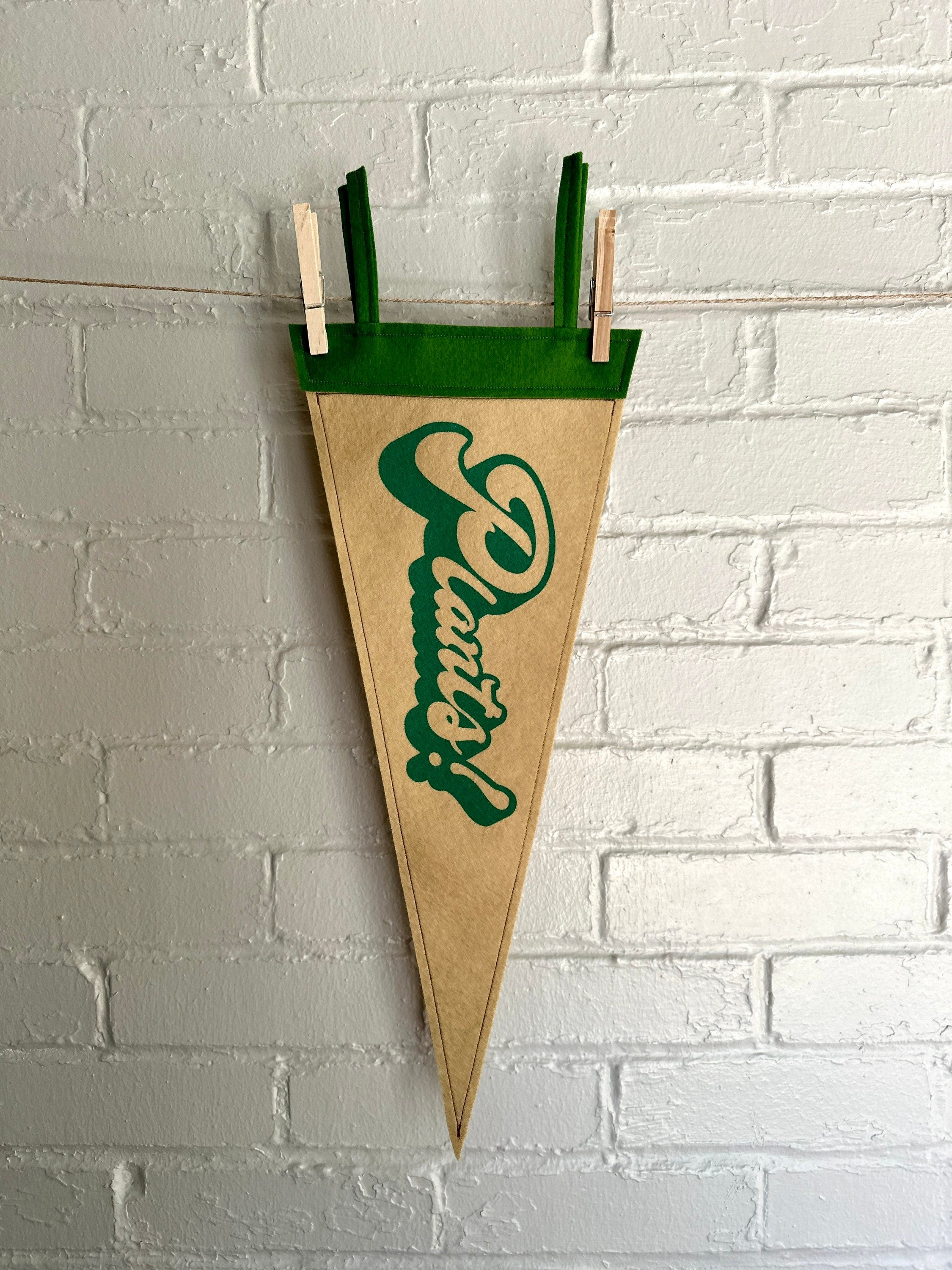 A light brown felt pennant with green trim and green lettering that reads "Plants!"
