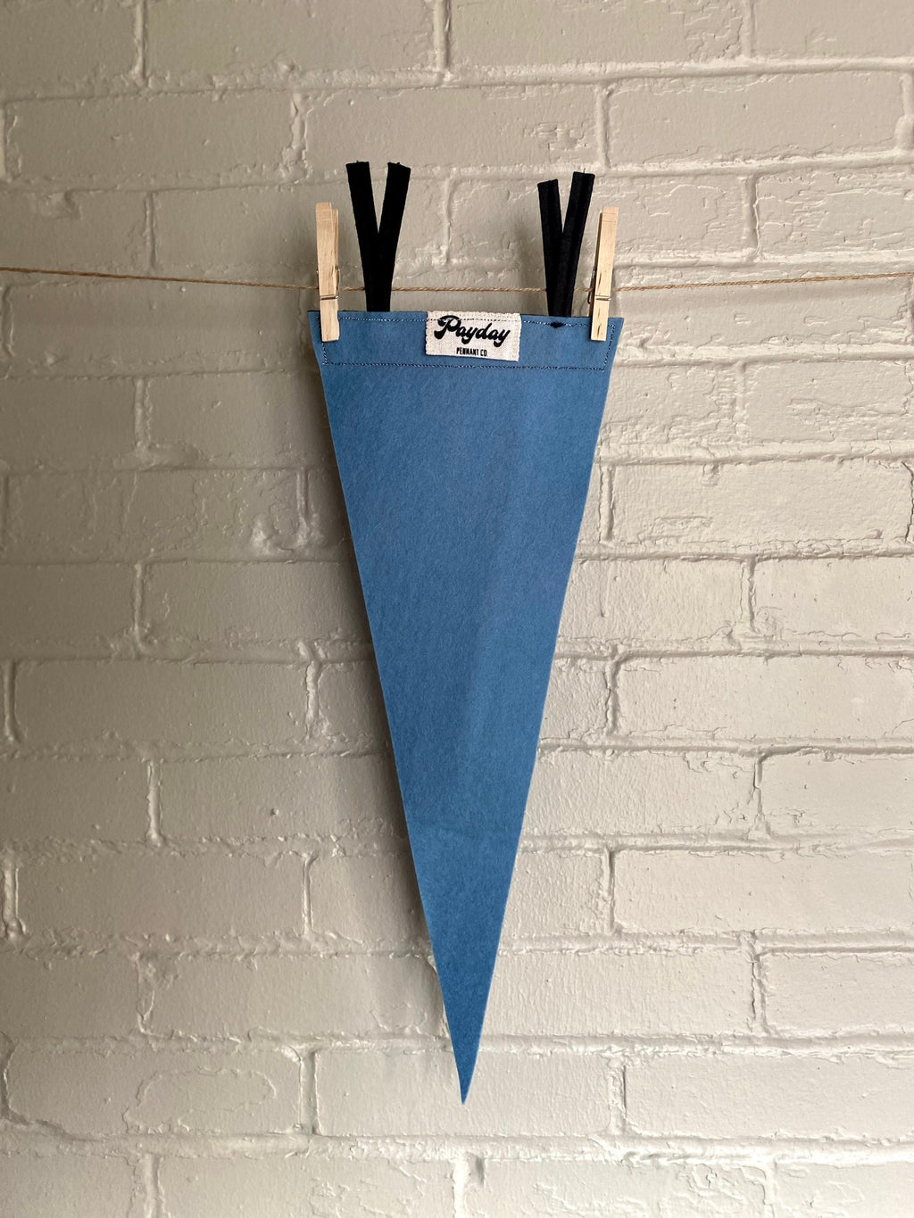 Back of a sky blue felt pennant with black trim and a logo for "Rusty's Day Camp for Boy Adventurers" printed in black ink