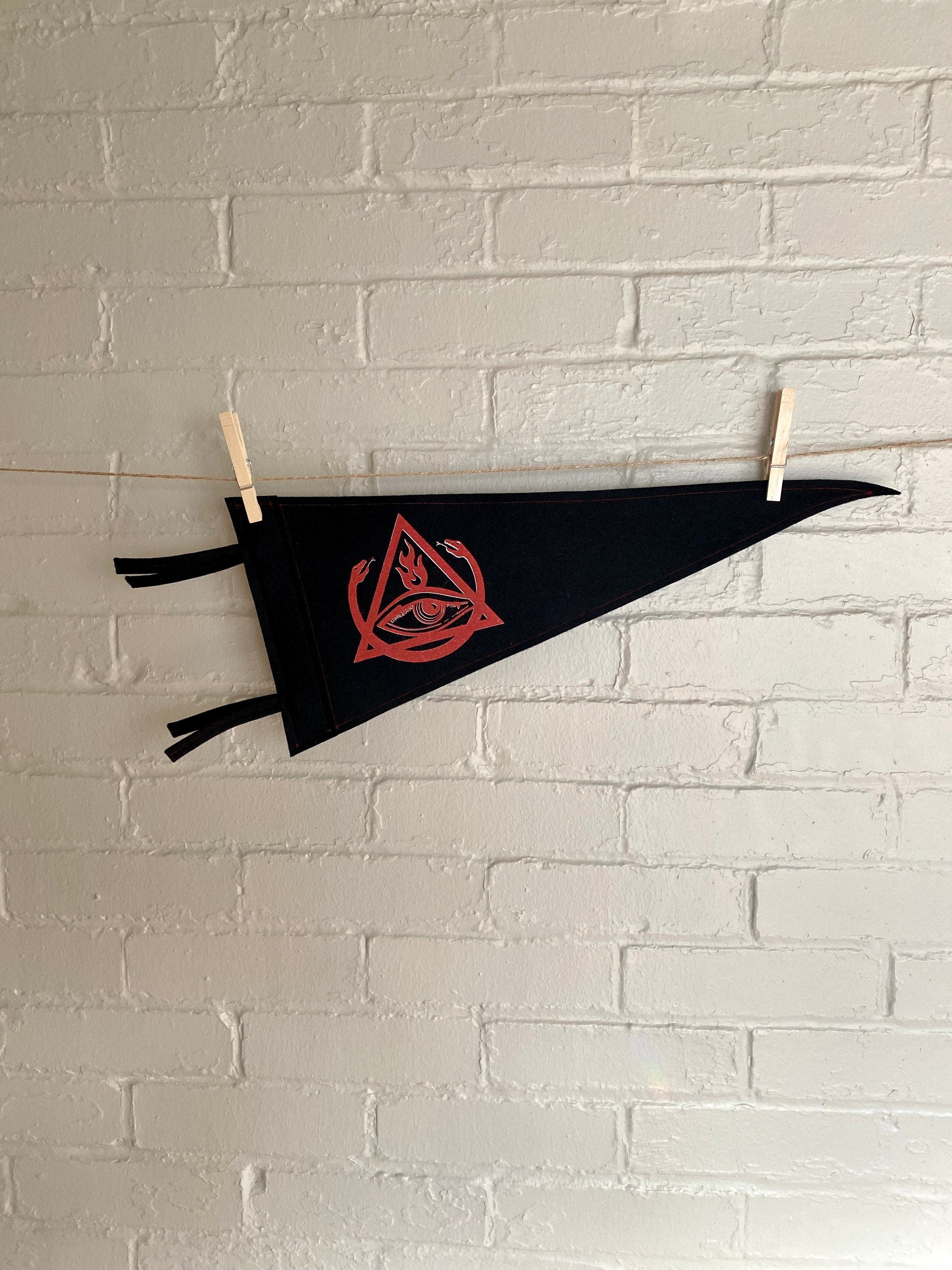 A black felt pennant with black trim and the Order of the Triad logo from The Venture Bros cartoon printed in red ink